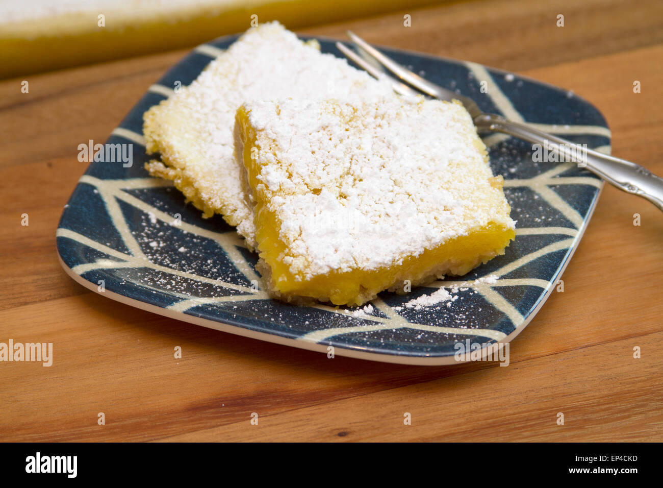 Lemon Bar serviert frisch gesichert und mit Puderzucker bedeckt.  Serviert auf einem blau-weißen Teller Stockfoto