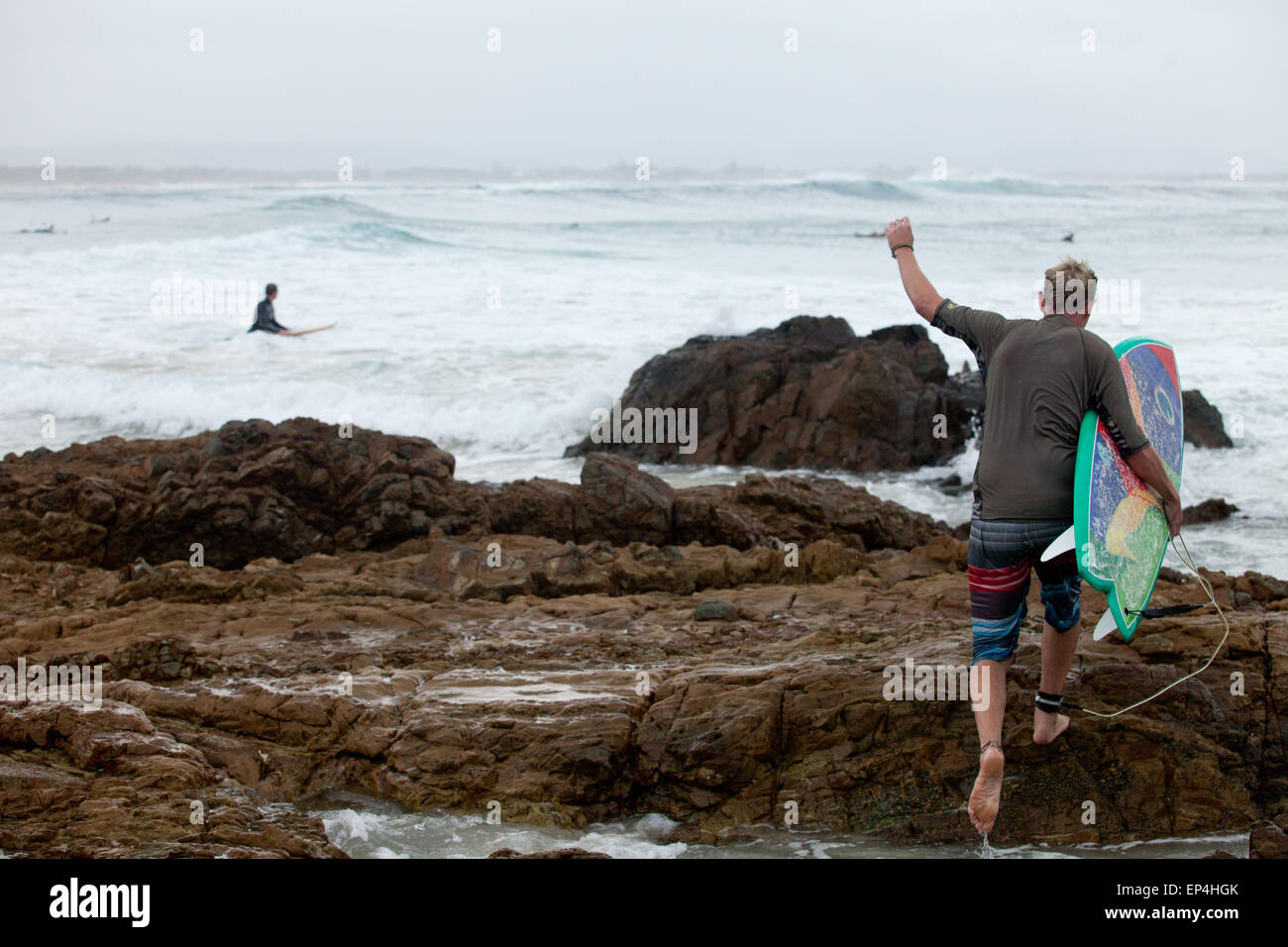 Eine Surfer verstärkt auf die Felsen in Byron Bay, Australien. Stockfoto