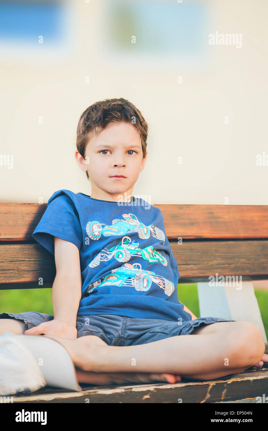 traurige Junge sitzt auf einer Bank Stockfoto