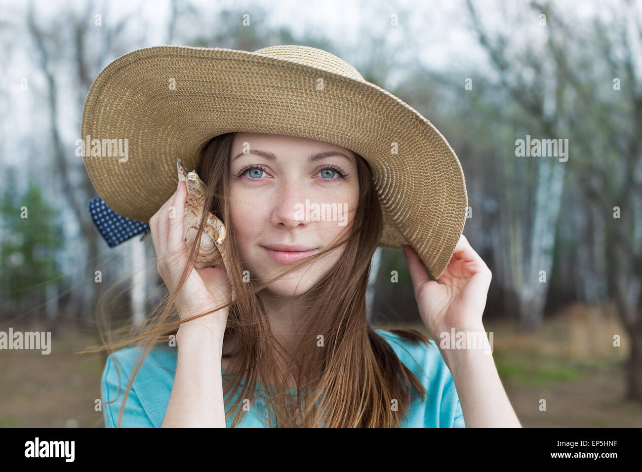 Glückliches Mädchen in Hut hören Muschel an einem windigen Tag Stockfoto
