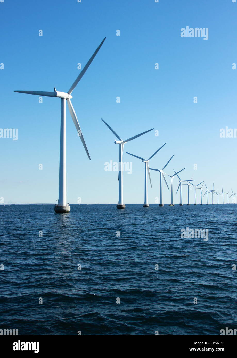 Vertikale Perspektive Linie der Ozean Windmühlen mit dunklen Wasser und Himmel Stockfoto