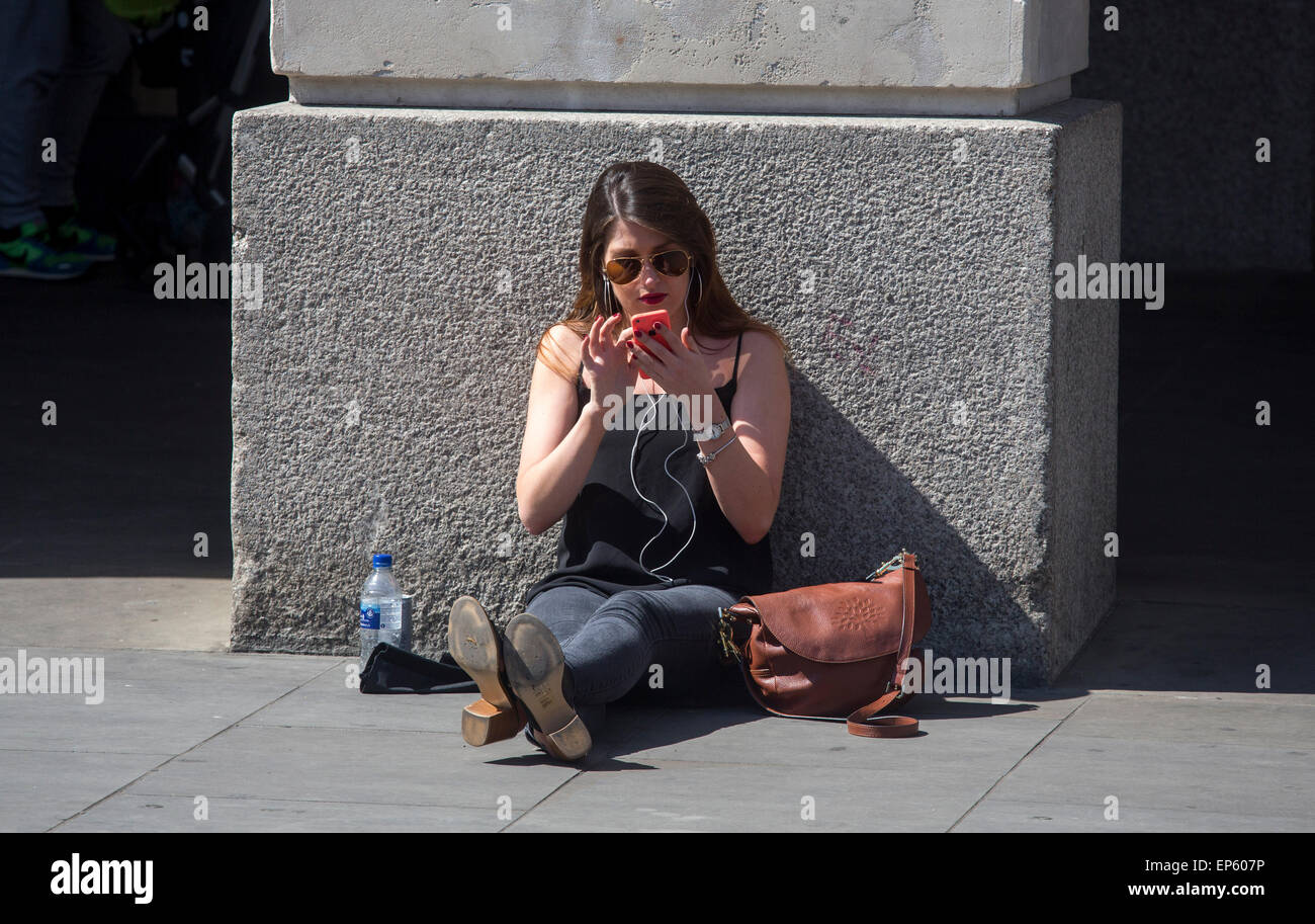 iPhone Handy-Benutzer Benutzer Sonnenschein betrachten ihre Telefone außerhalb der Apple-Store in Covent Garden Stockfoto