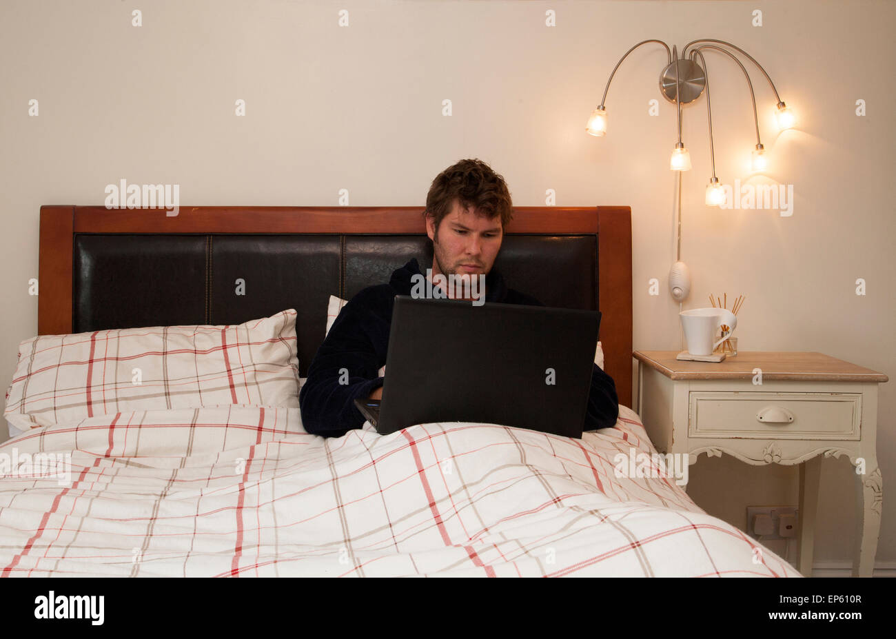 männlichen Erwachsenen arbeiten von zu Hause im Bett Stockfoto