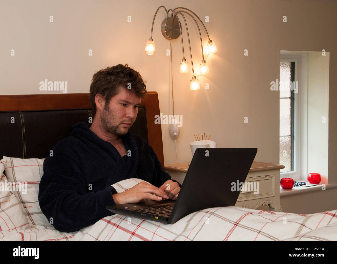 männlichen Erwachsenen arbeiten von zu Hause im Bett Stockfoto