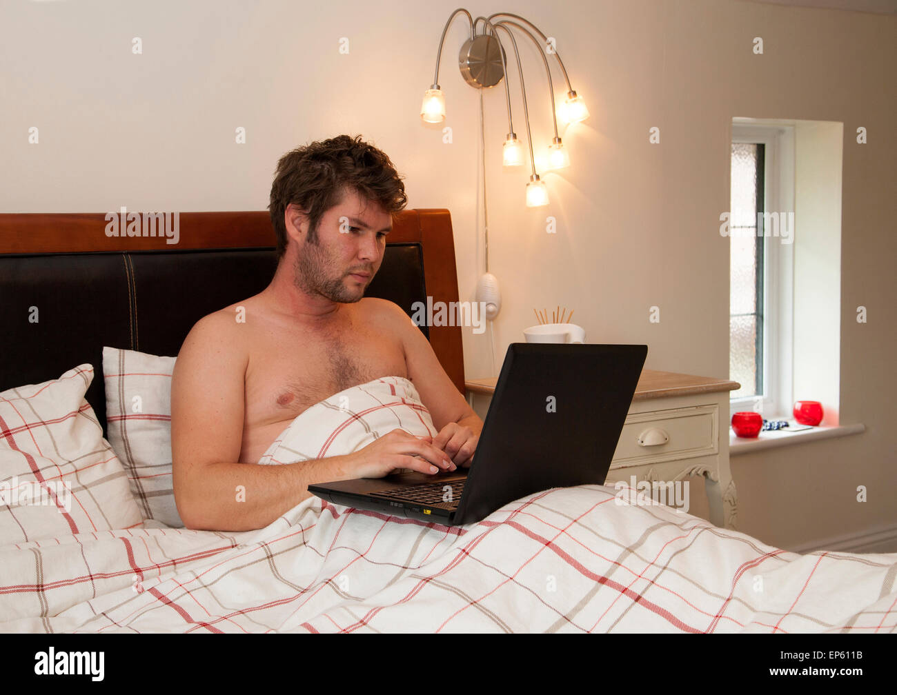 männlichen Erwachsenen arbeiten von zu Hause im Bett Stockfoto