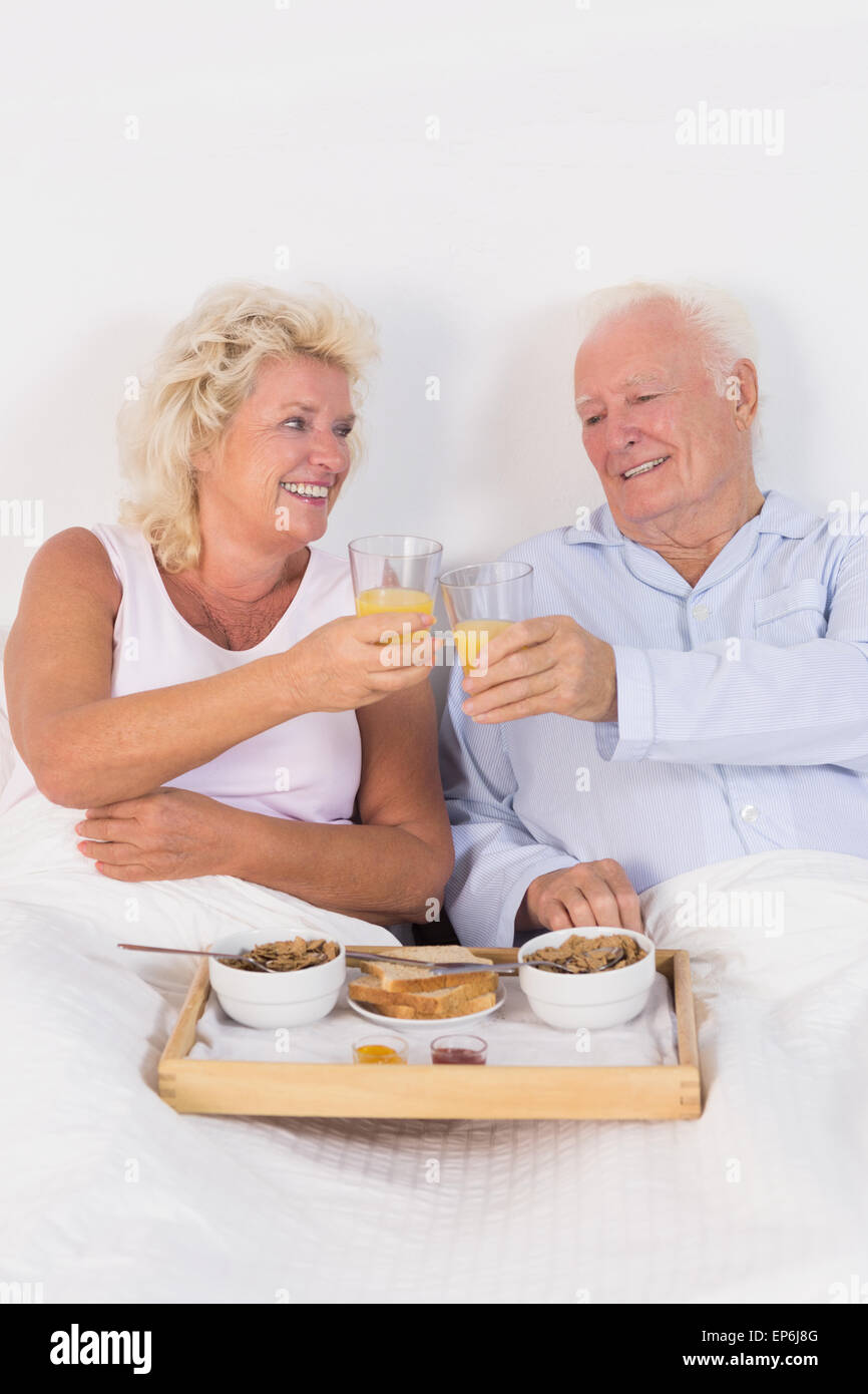 Altes Paar Toasten beim Frühstück mit Orangensaft Stockfoto