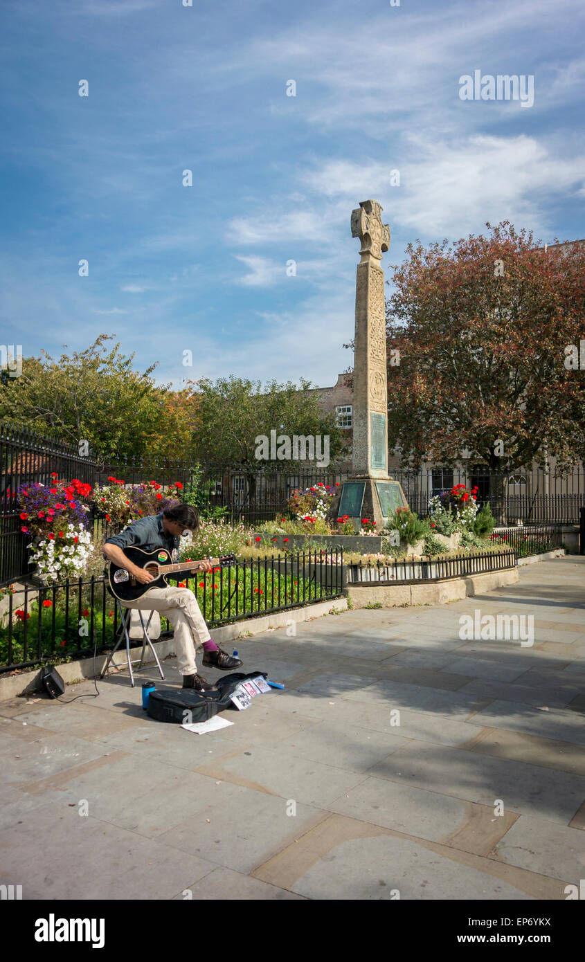 Straßenmusikant Gitarre neben der keltischen Gedenkstätte Kreuz in der High Street Stockfoto