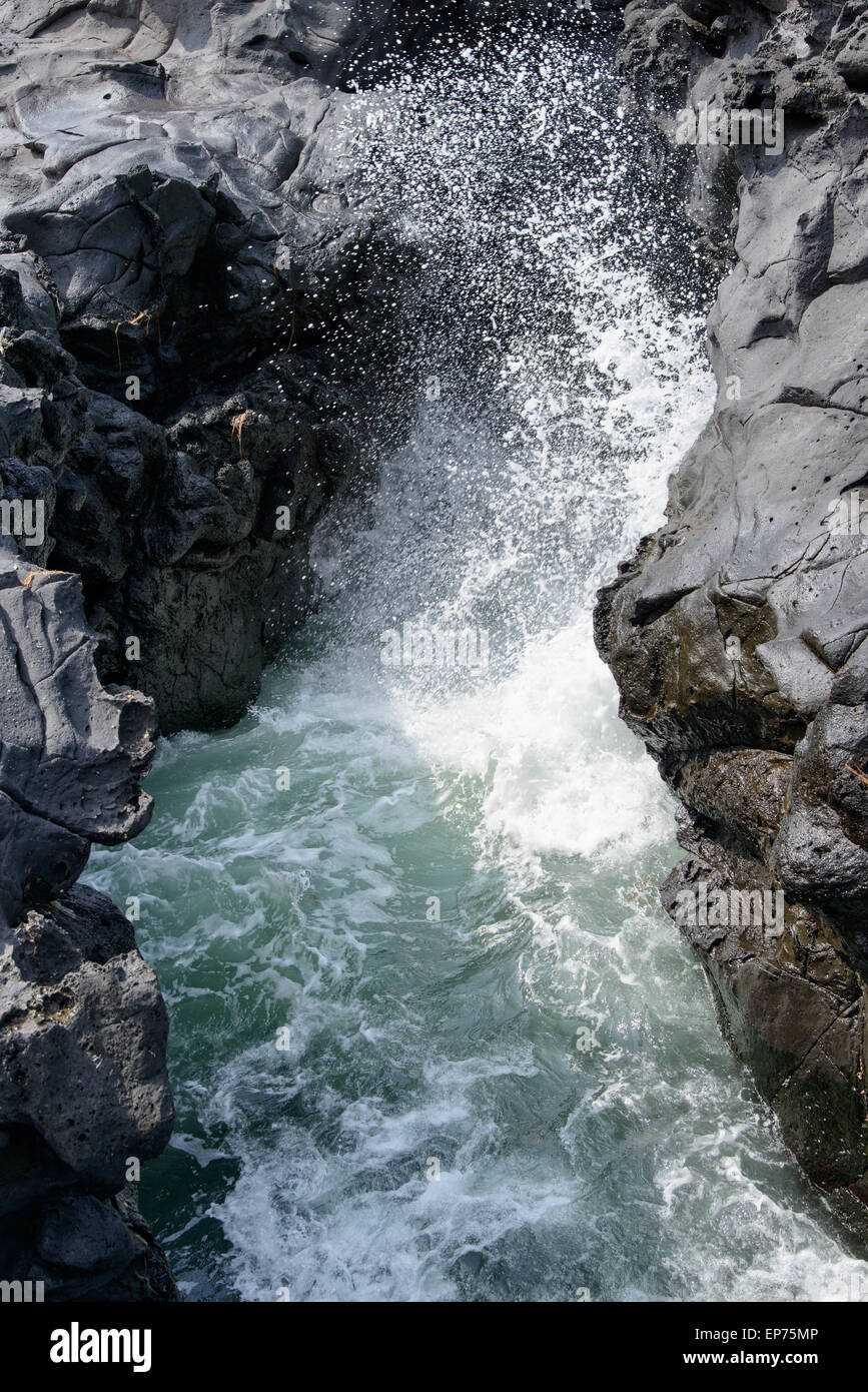 Spray des Wassers durch schlug Meerwasser durch Tunnel zwischen Felsen an der Küste in Insel Jeju, Korea. Stockfoto