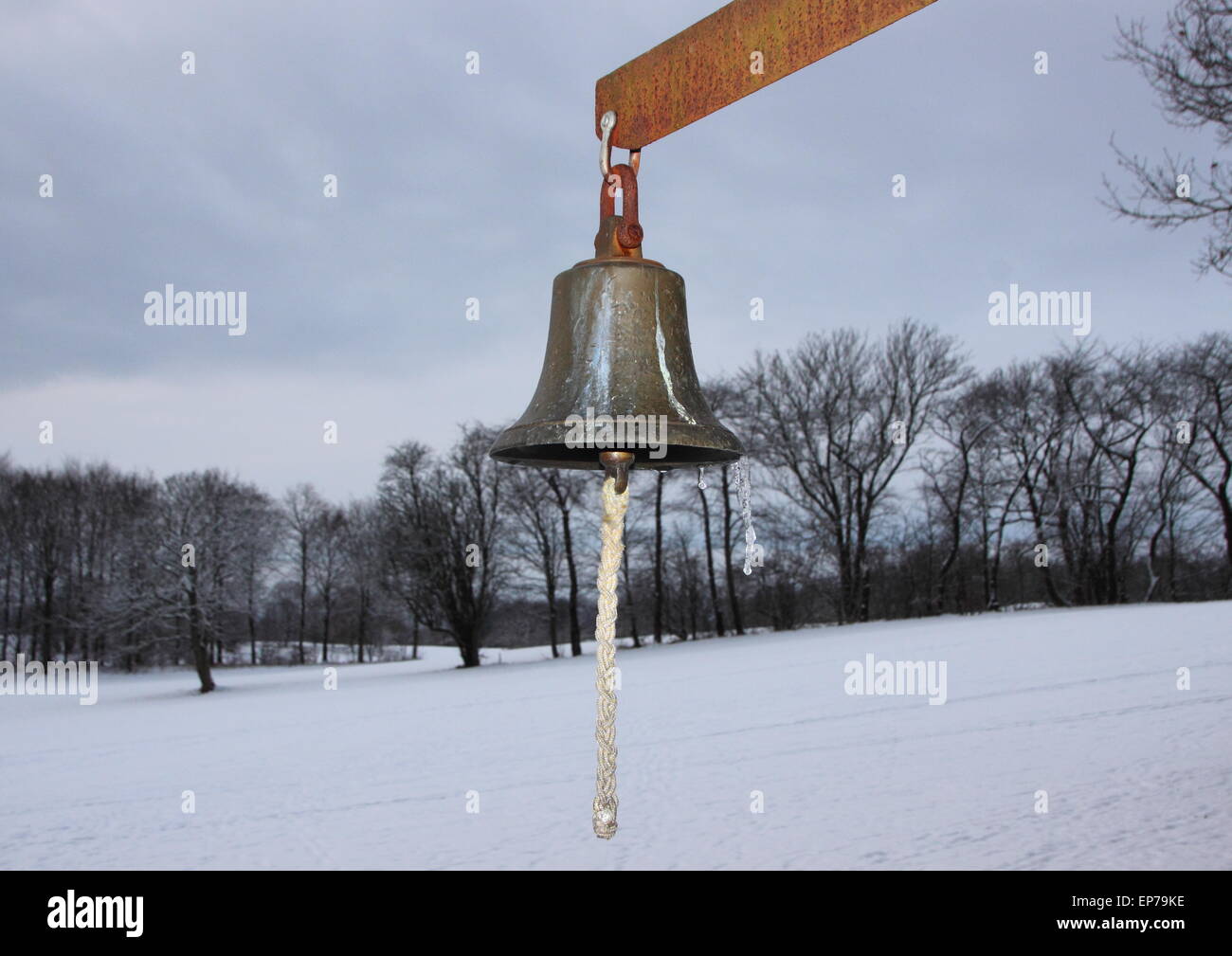 Metall-Glocke mit Winter verschneiten Feldern im Hintergrund. Die Glocke wird auf einem Golfplatz verwendet. Stockfoto