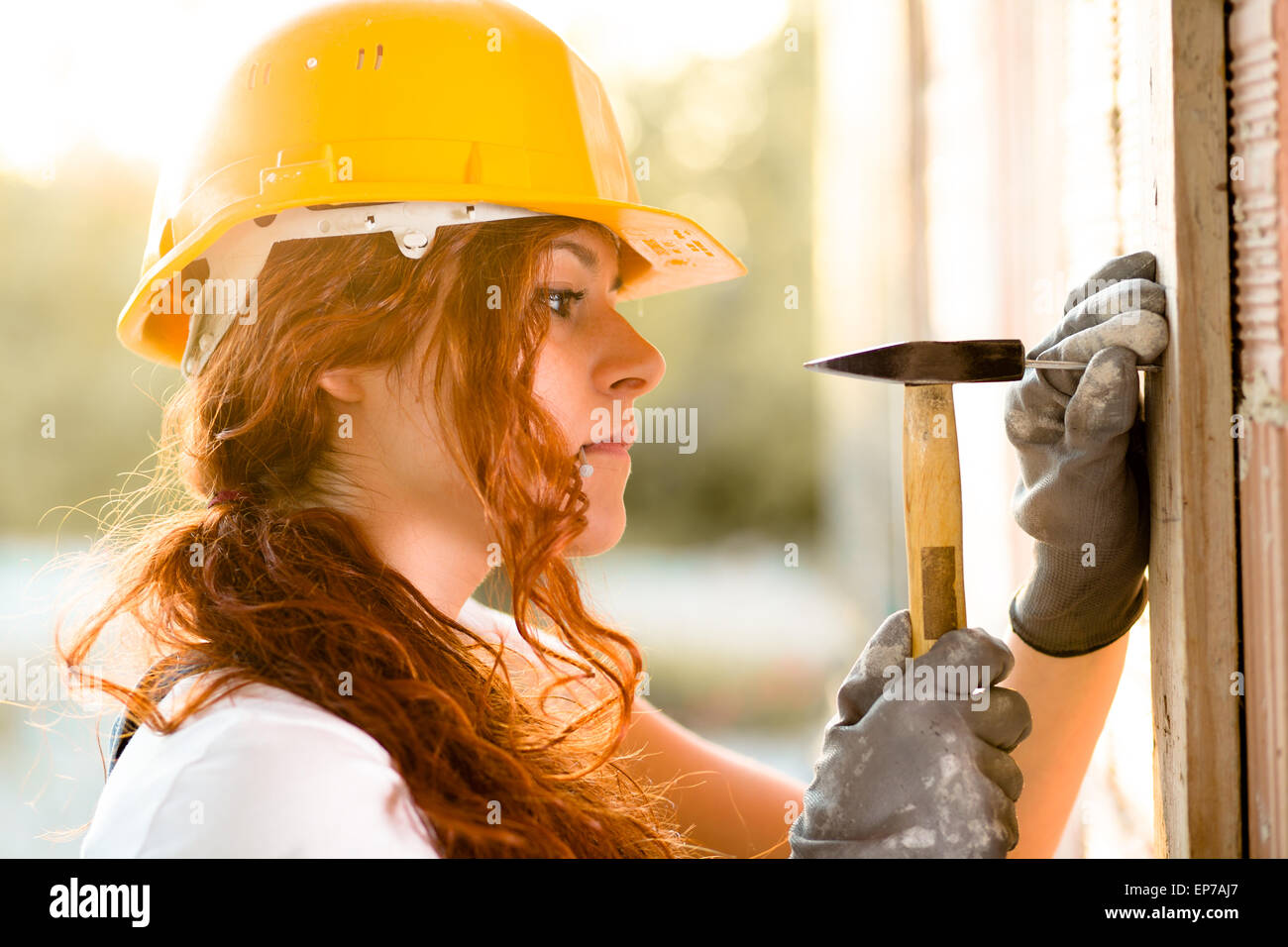 Frau Maurer mit Helm, einen Nagel mit einem Hammer schlagen Stockfoto