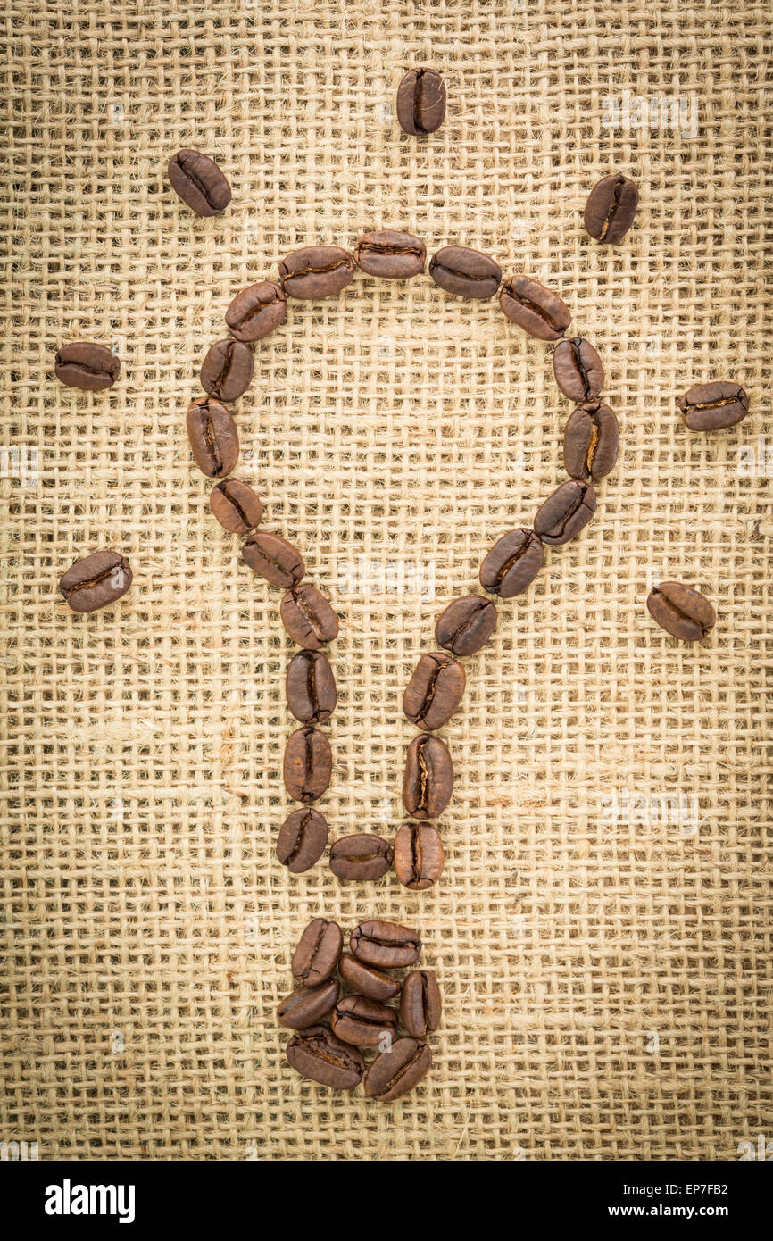 Glühbirne, gemacht aus Kaffeebohnen mit Lichtstrahlen Stockfoto