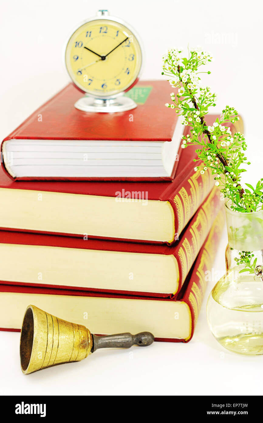 Zeit zum lesen. Ein Stapel von Büchern, einem Zweig der Blütenpflanzen, Wecker und Glocke Stockfoto