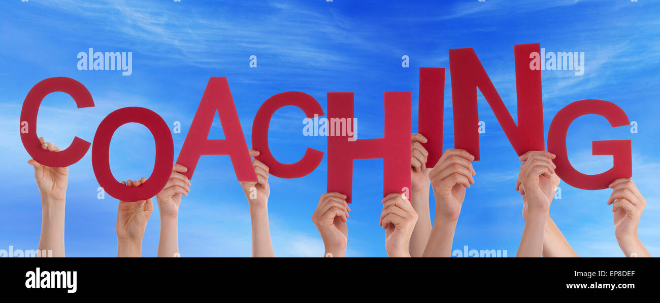 Viele Menschen Hände halten rote Wort Coaching blauer Himmel Stockfoto