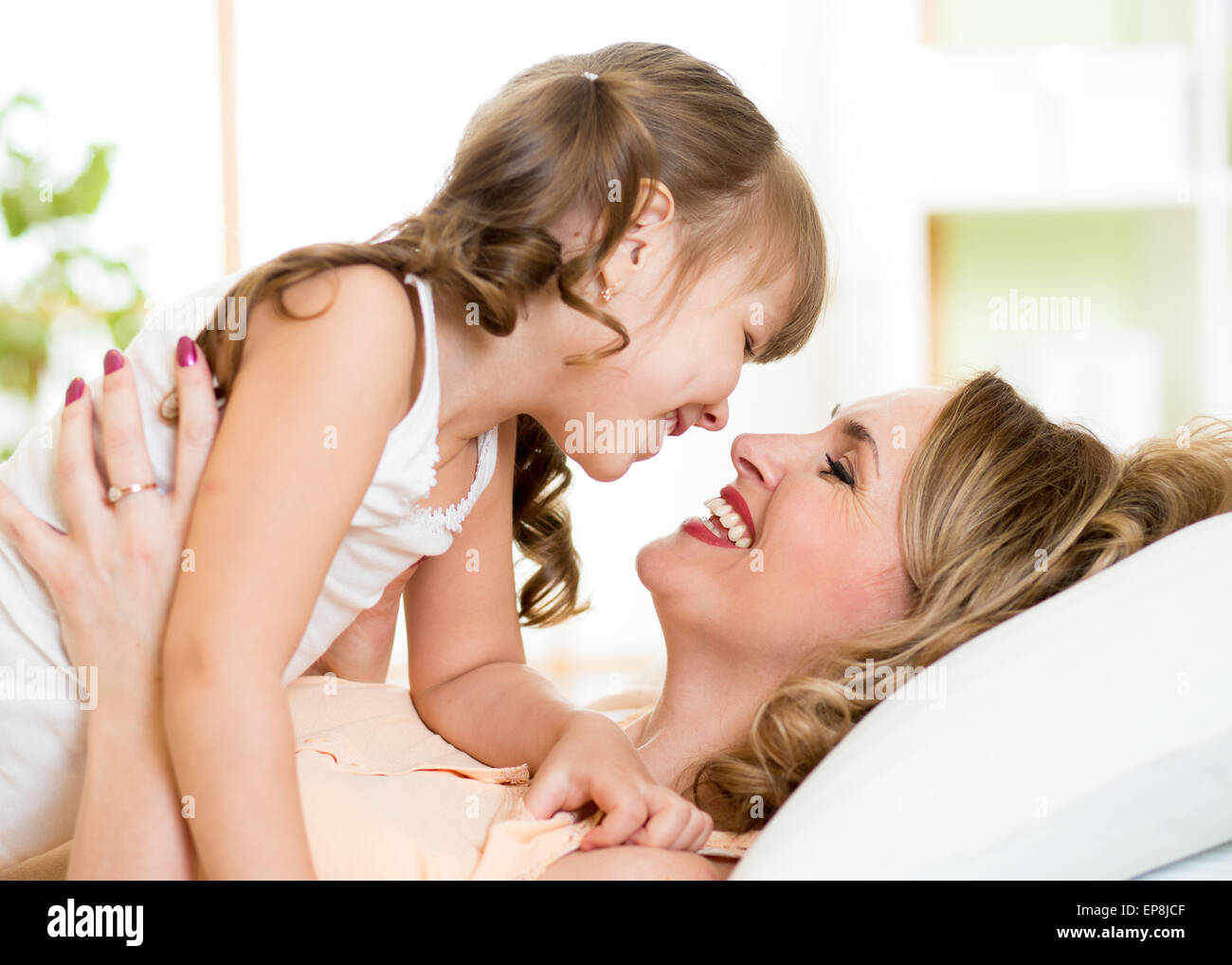 Glückliche Mama spielt mit ihrem Kind im Bett genießen sonnige Morgen im Hause Schlafzimmer Stockfoto
