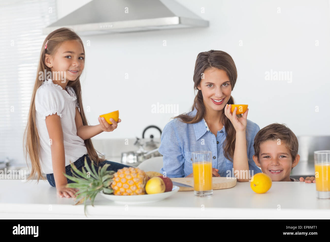 Geschwister, die Anhebung einer halben Orange in der Küche Stockfoto
