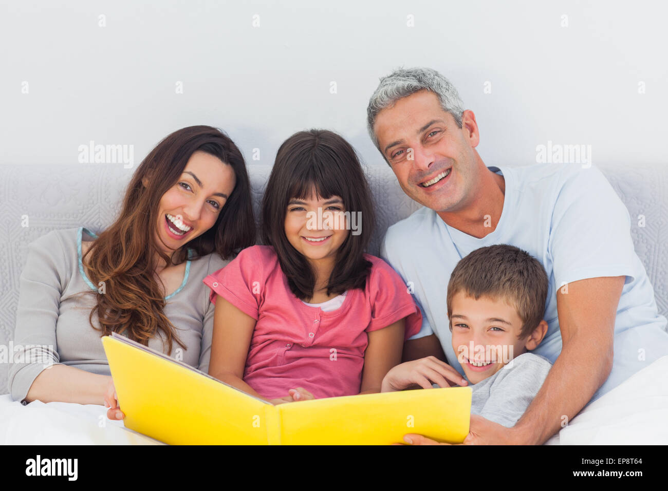 Lächelnd Familie betrachten gemeinsam ihr Fotoalbum im Bett Stockfoto