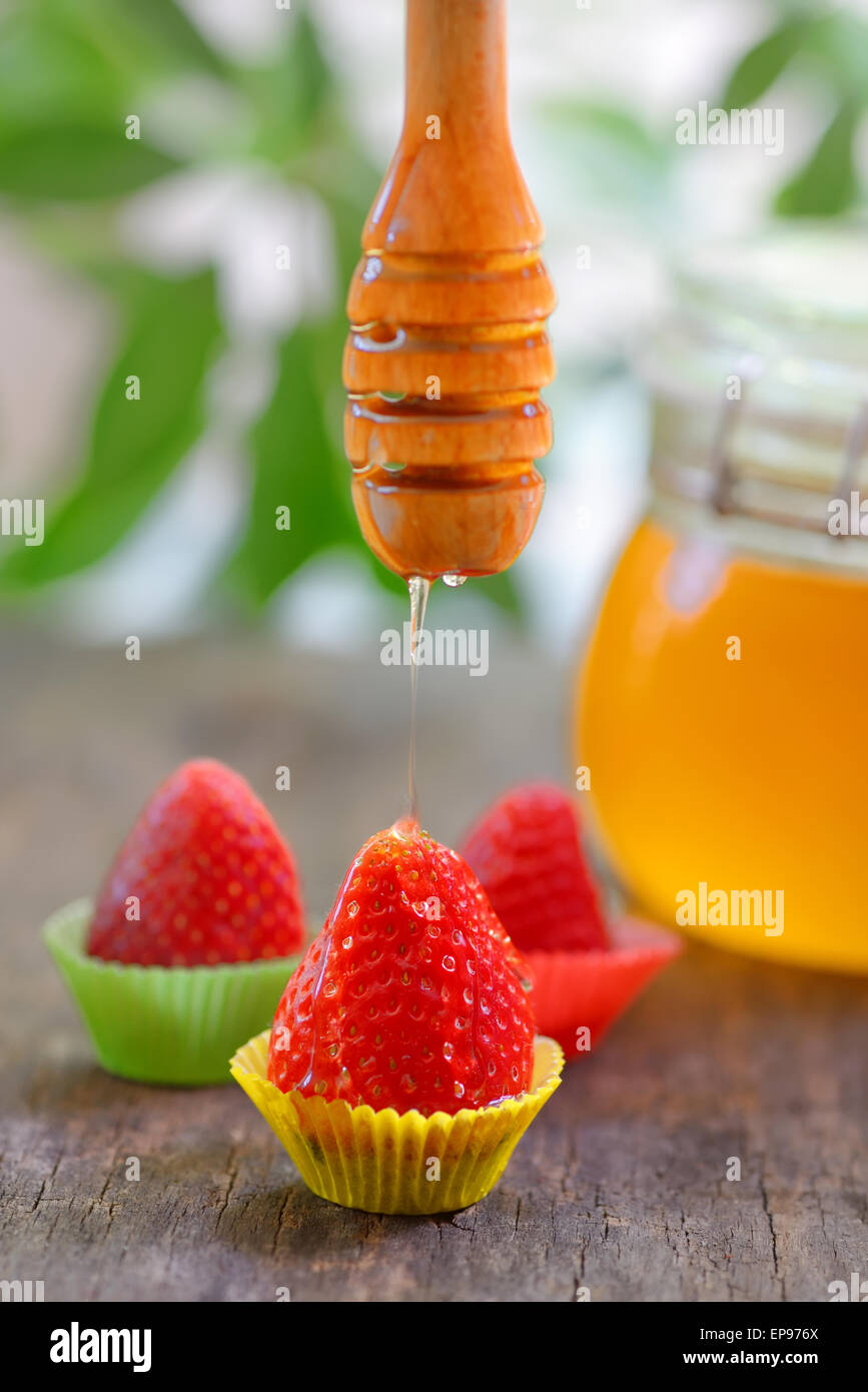 Erdbeere mit Honig tropft auf die alte Tabelle Stockfoto