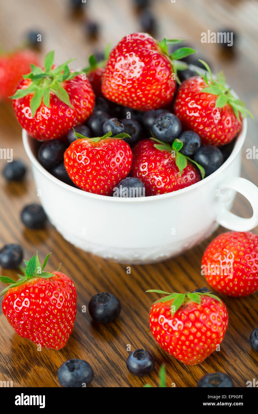 Schale mit Erdbeeren und Heidelbeeren auf einem Holztisch Stockfoto
