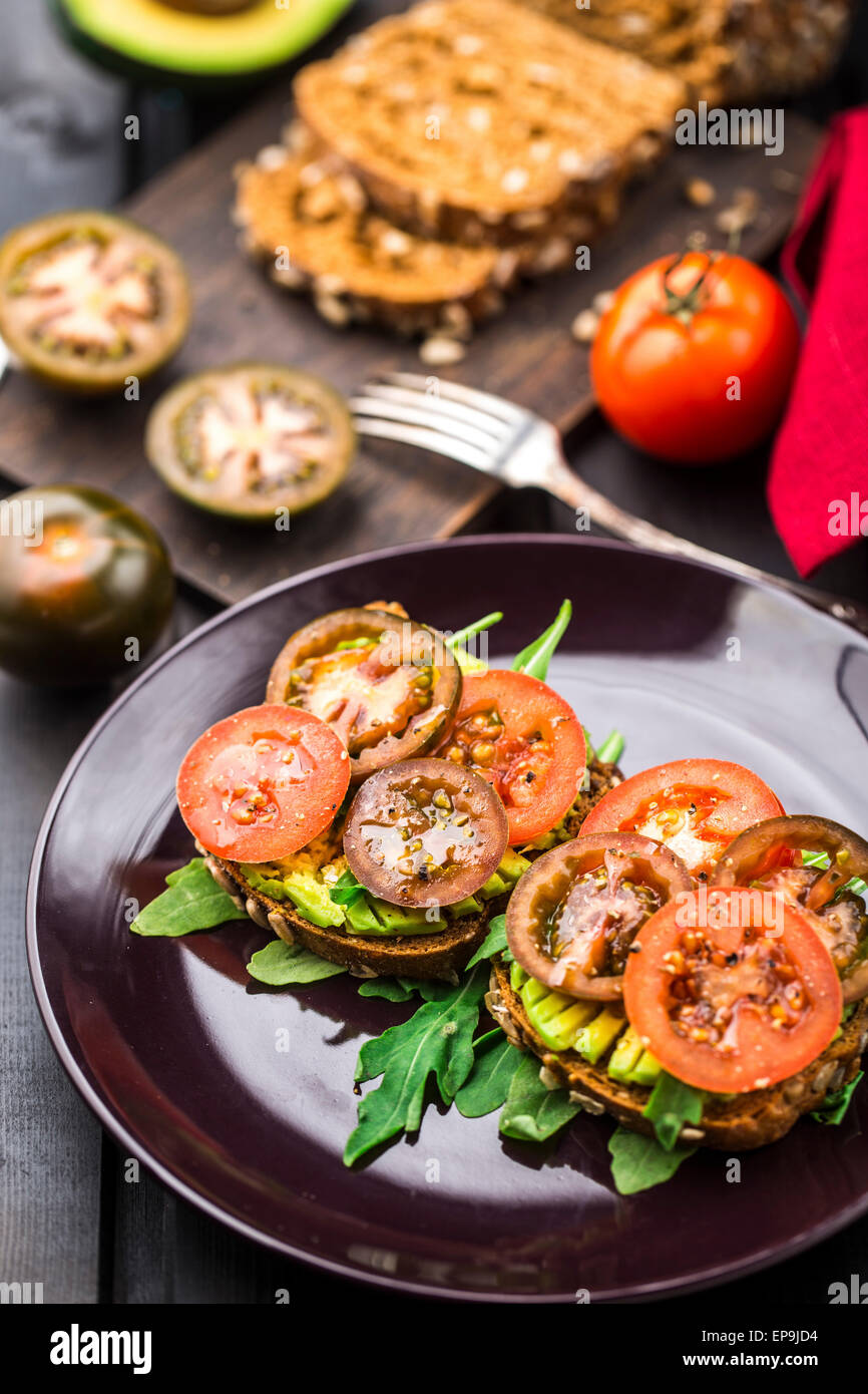 Avocado-Sandwich mit Rucola und Tomaten auf einem Teller Stockfoto