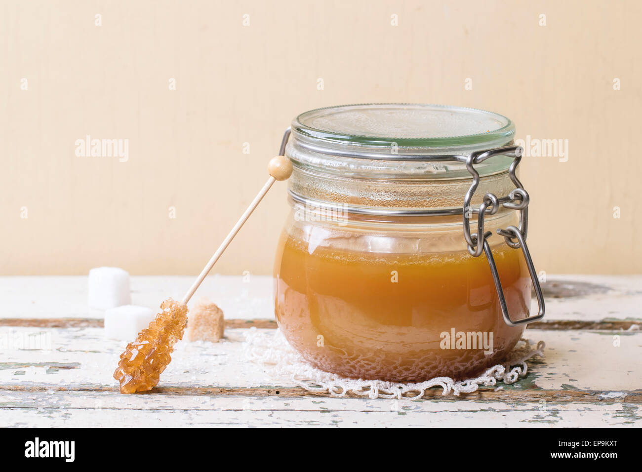 Glas hausgemachte Karamell-Sauce, serviert mit Würfelzucker auf Holztisch Stockfoto