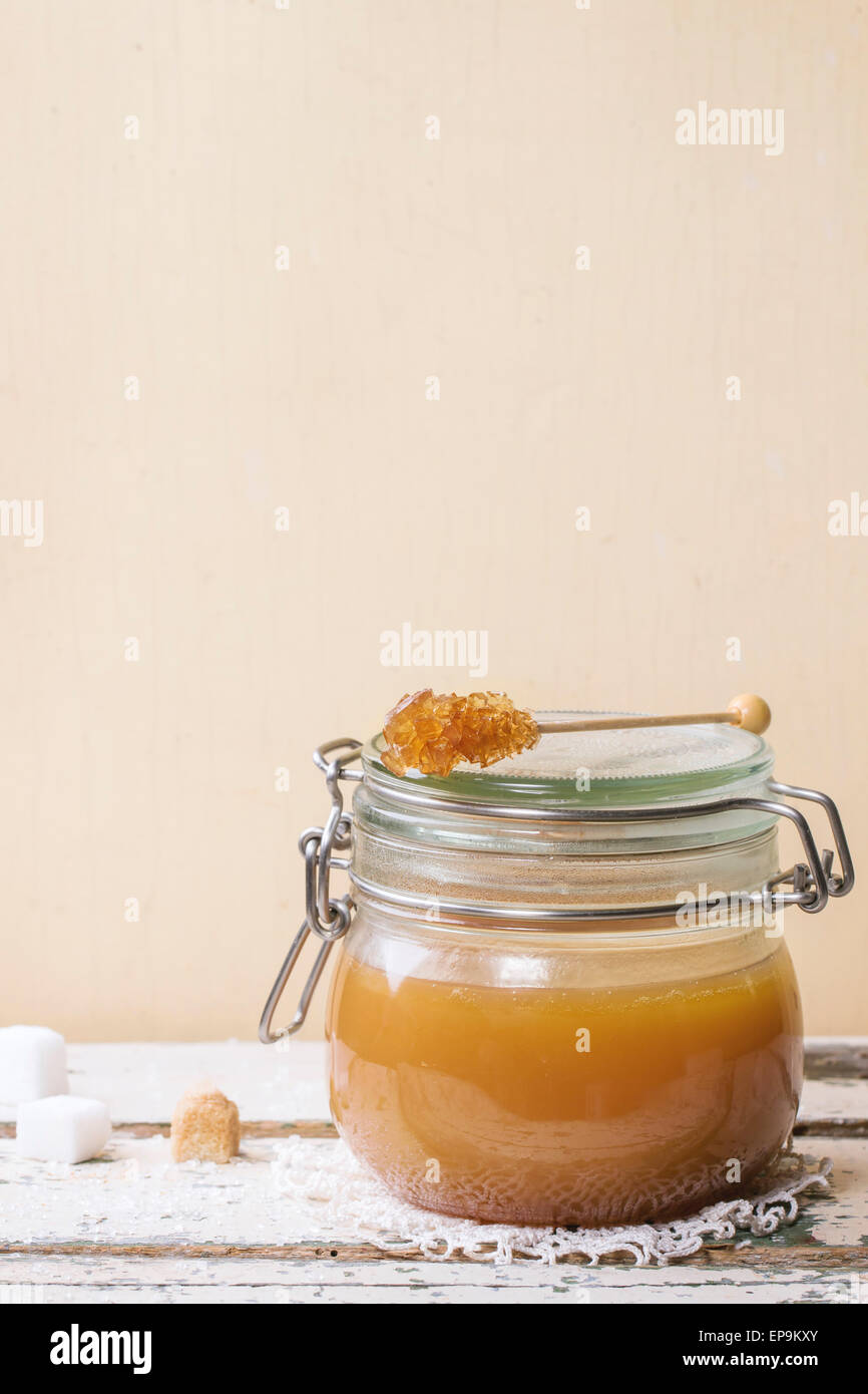 Glas hausgemachte Karamell-Sauce, serviert mit Würfelzucker auf Holztisch Stockfoto