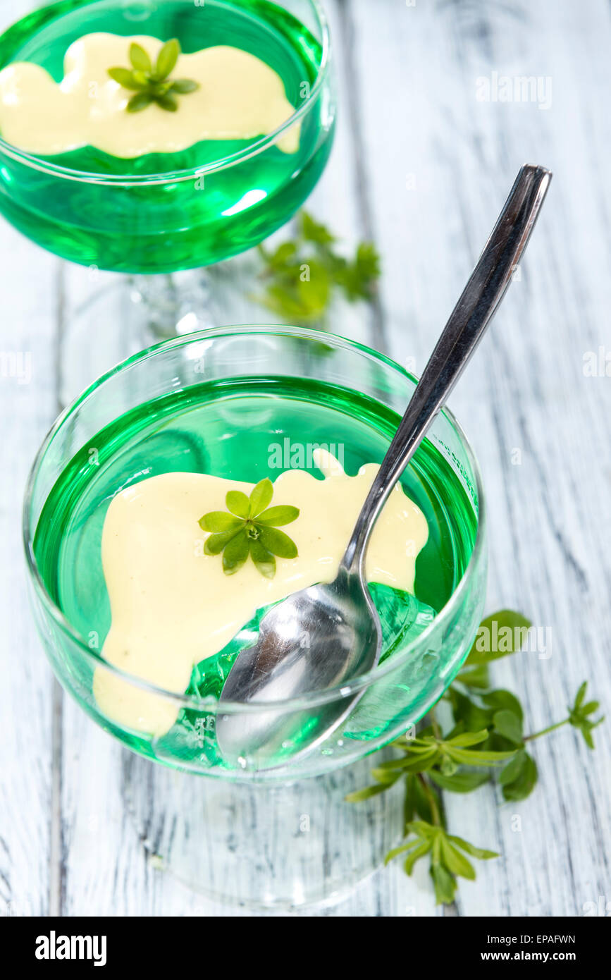 Waldmeister-Gelee mit Vanillesauce (auf hölzernen Hintergrund ... Waldmeister-Gelee mit Vanillesauce (auf hölzernen Hintergrund ...