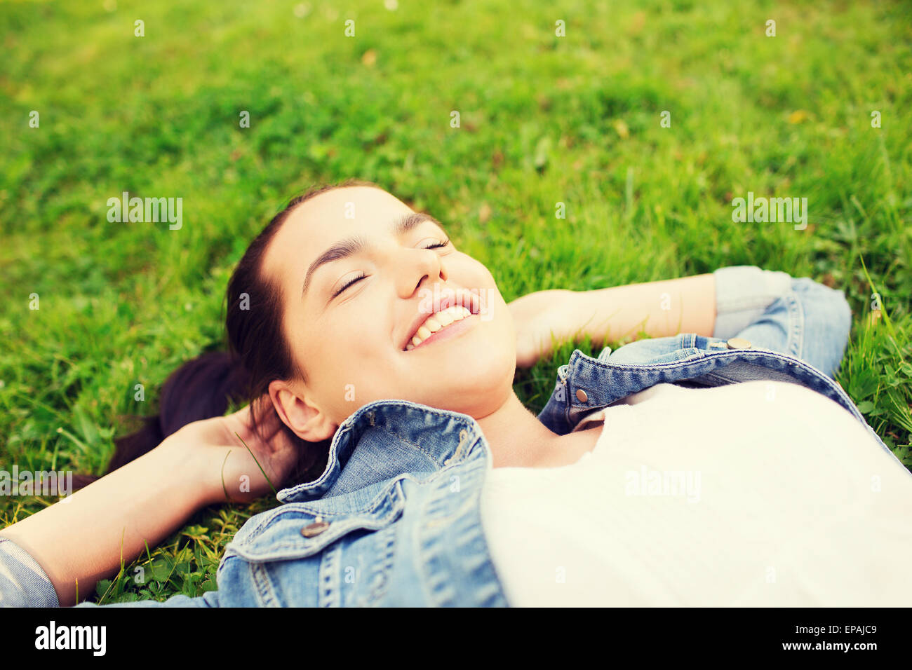 lächelnd junges Mädchen mit geschlossenen Augen liegen auf dem Rasen Stockfoto