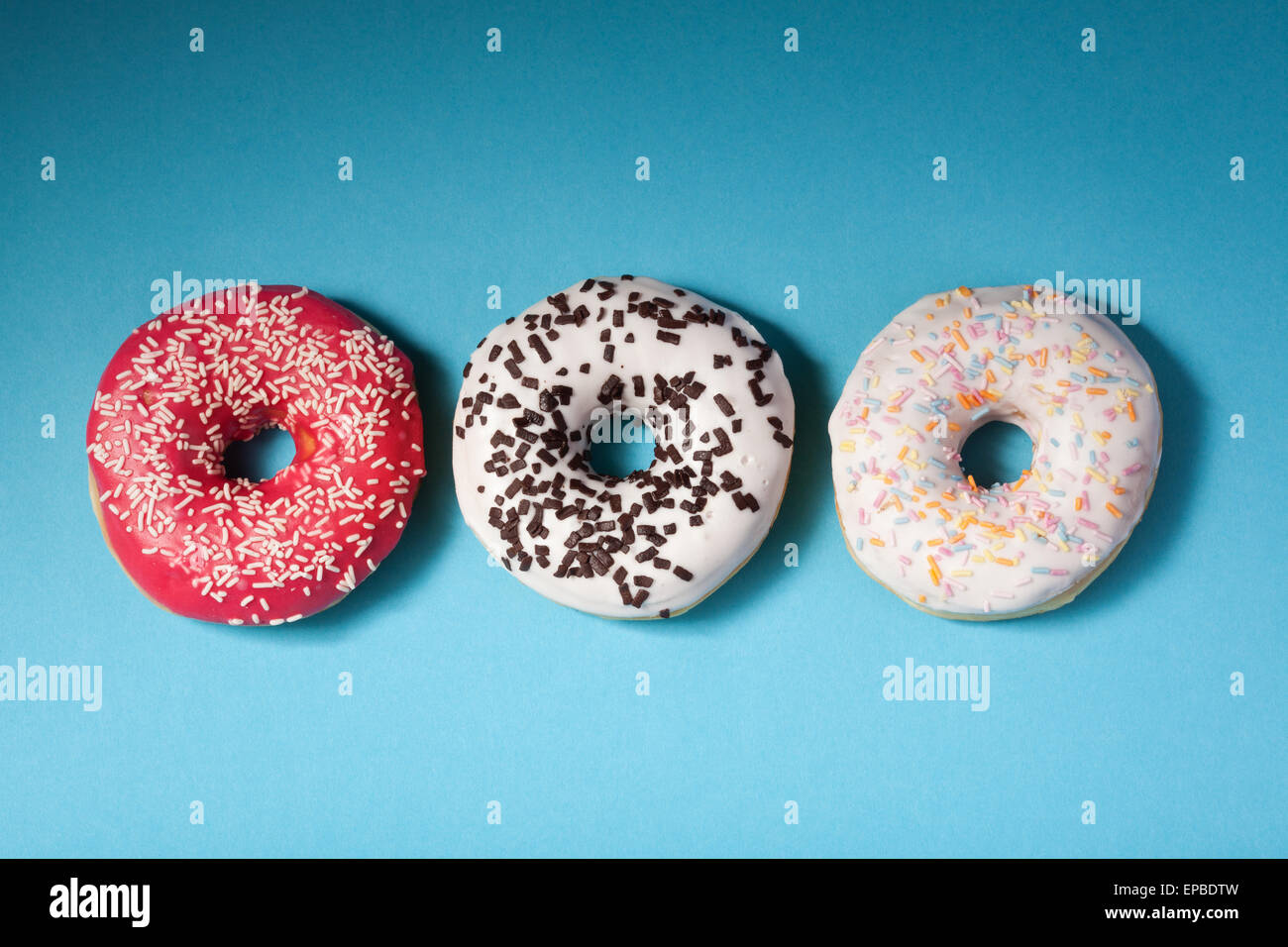 Draufsicht von drei Donuts isoliert auf blau Stockfoto