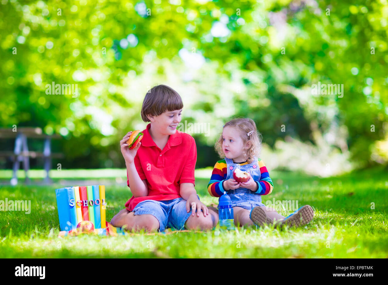 Kinder im Schulhof. Happy Lachen Jugendlicher Student junge und Vorschule Mädchen im Garten Schule, die Bücher zu lesen Stockfoto