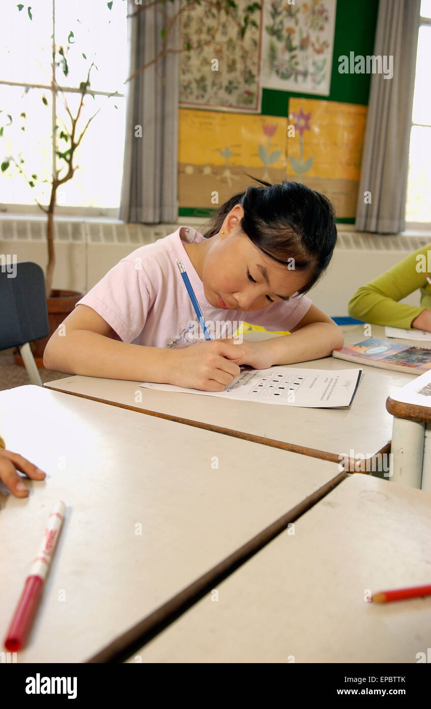 Klasse 3 weibliche Schüler arbeiten an ihrem Schreibtisch Stockfoto