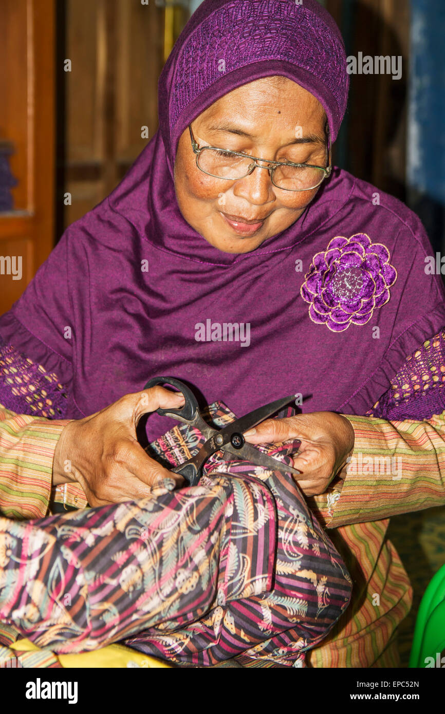 Frau ausbessern eine Kleidungsstück bei einem Lurik Workshop in Cawas Dorf, Klaten, Java, Indonesien Stockfoto