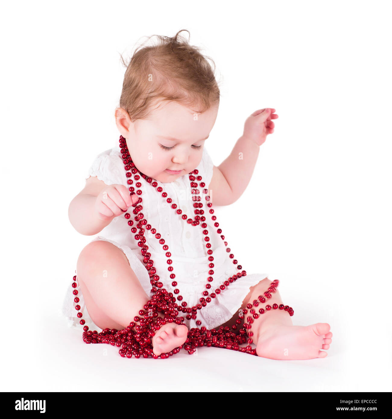 Lustige Babymädchen spielen mit roten Perlen Stockfoto