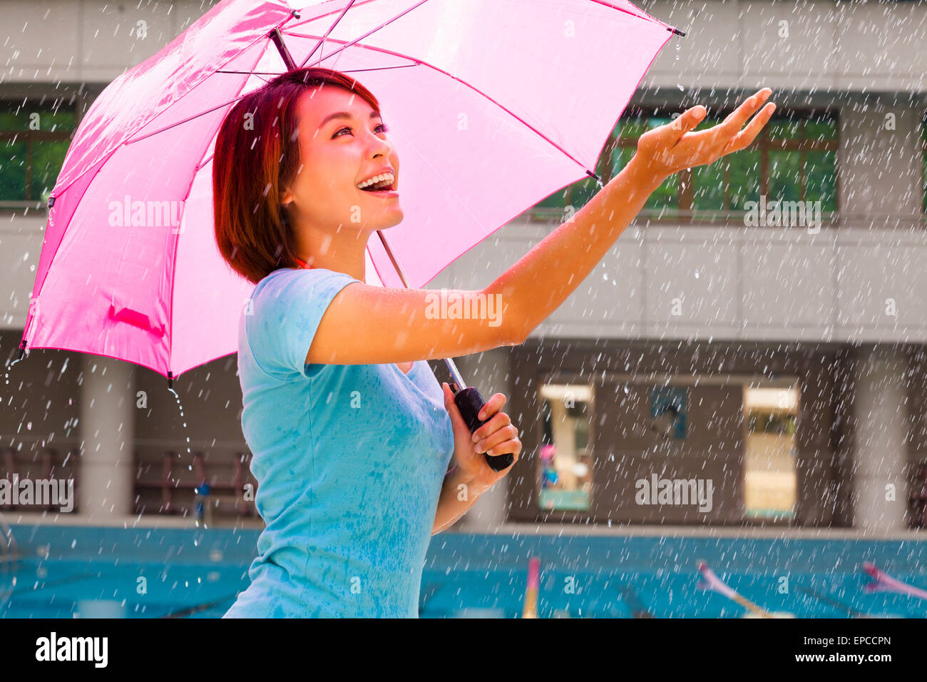 Schöne junge Frau unter rosa Regenschirm Stockfoto