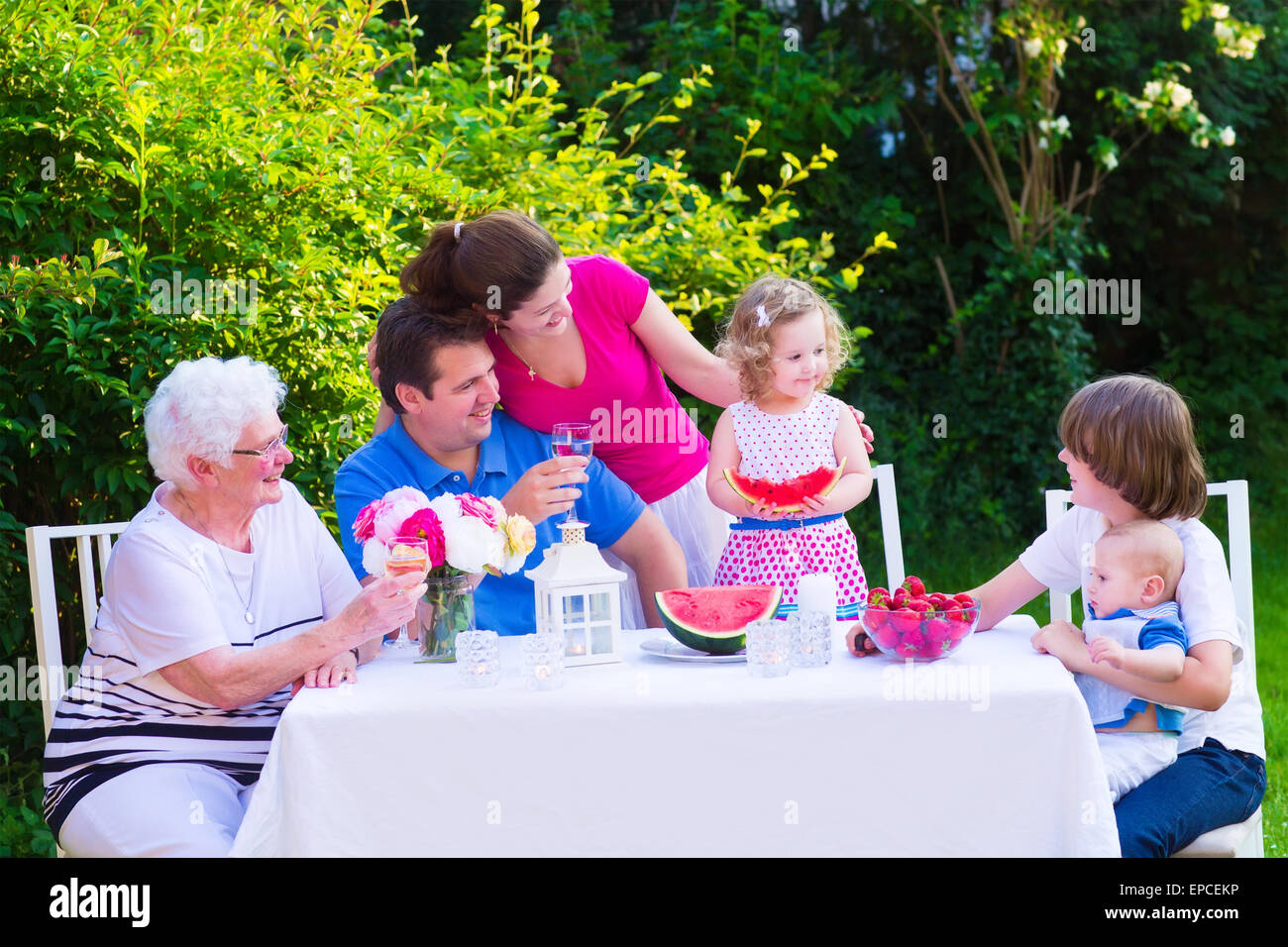 Glückliche große Familie Mittagessen mit Großmutter Verzehr von Obst, Wassermelone und Erdbeere im Garten genießen Stockfoto