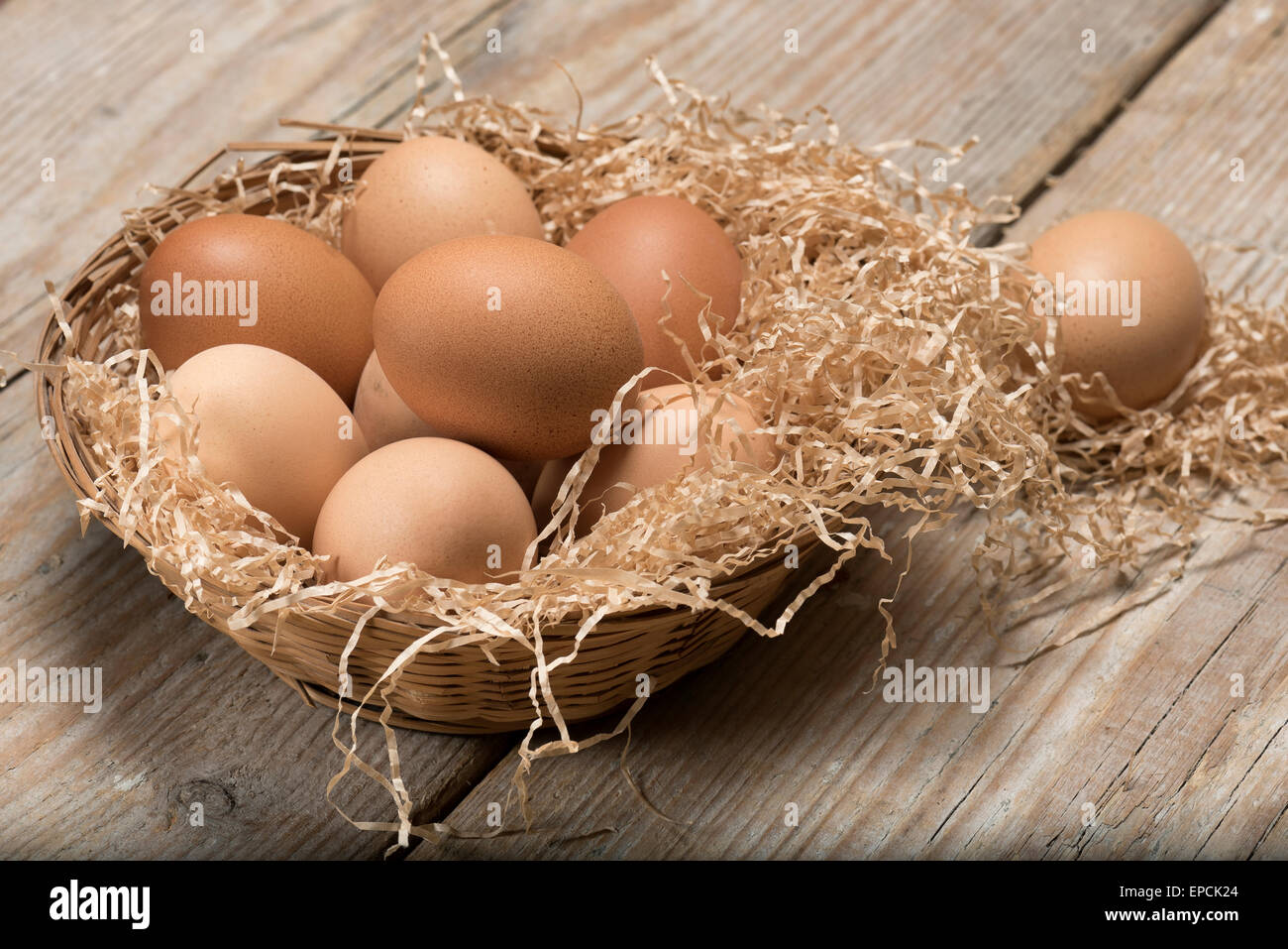 Gruppe von Eiern in Stroh Korb auf Holztisch Stockfoto