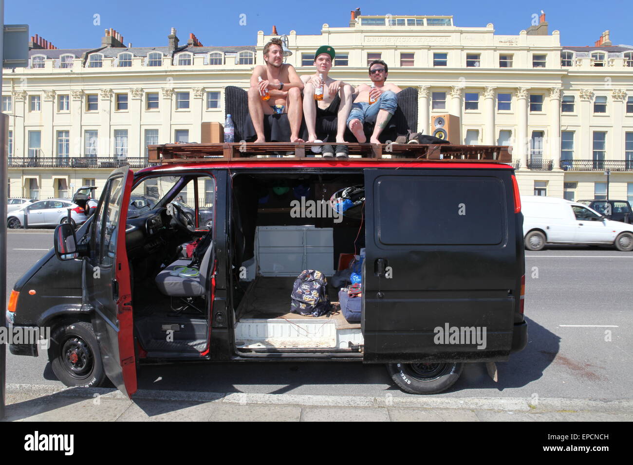 Drei junge Männer trinken Bier auf einem Sofa auf einem Lieferwagen in der Sonne auf Samstag, 16. Mai 2015 in Brighton, UK Stockfoto