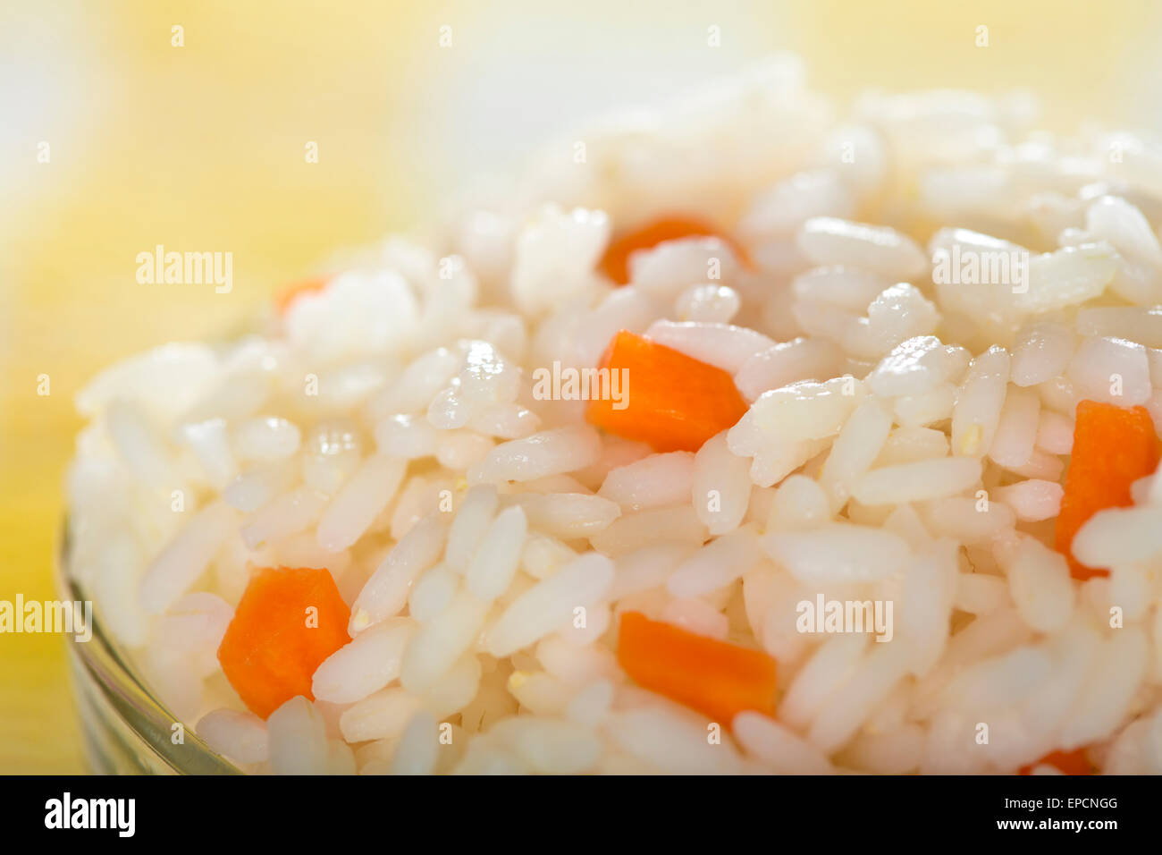 Schüssel voller Reis und Karotten mit gelbem Hintergrund Stockfoto