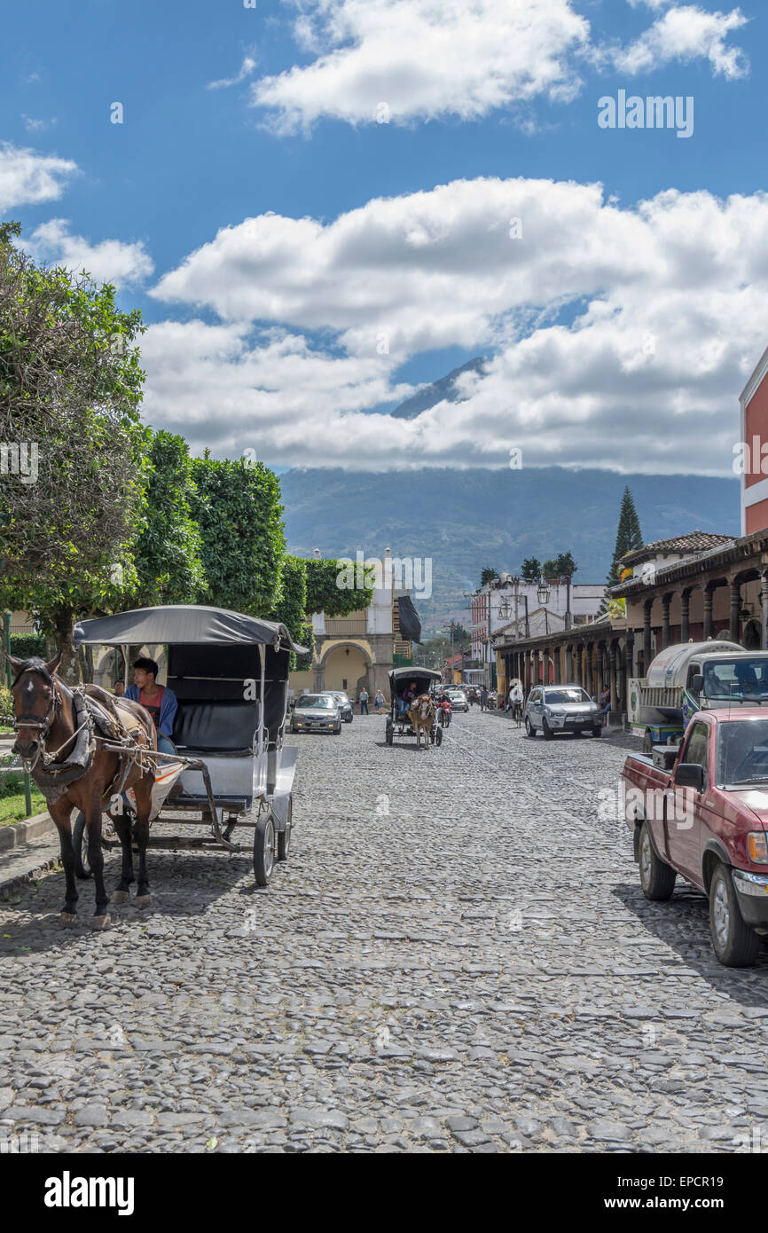 Straßenszene in Antigua Guatemala in der Nähe von Parque Central oder Central Park Plaza mit dem Vulkan Vulcan de Agua hinter teilweise in Wolken gehüllt. Stockfoto