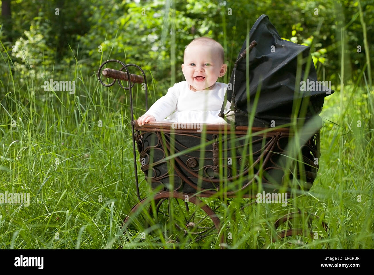 Babymädchen sitzt in einem Vintage Kinderwagen Stockfoto