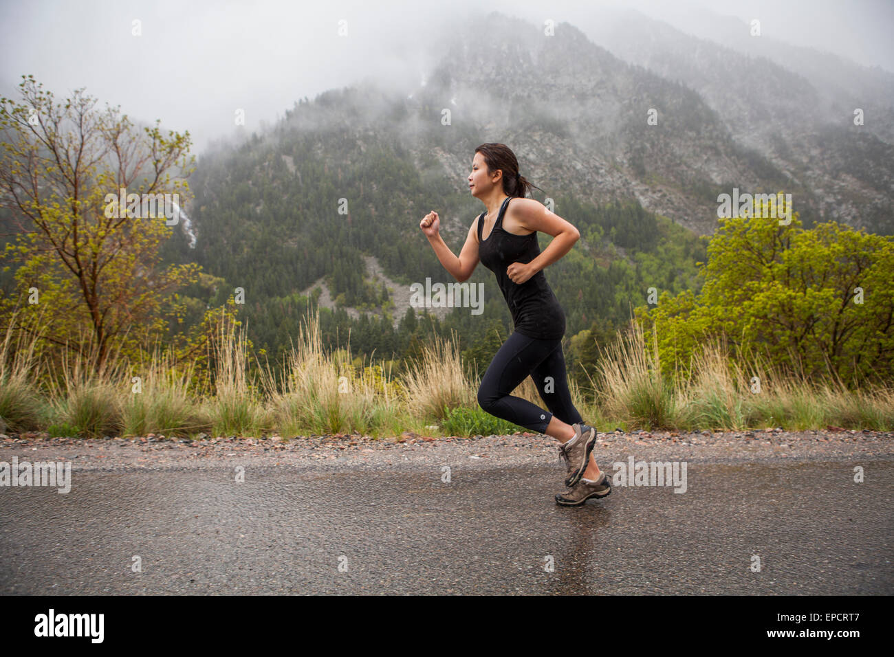 asiatische Frau laufen im Regen unterwegs in Bergen Stockfoto