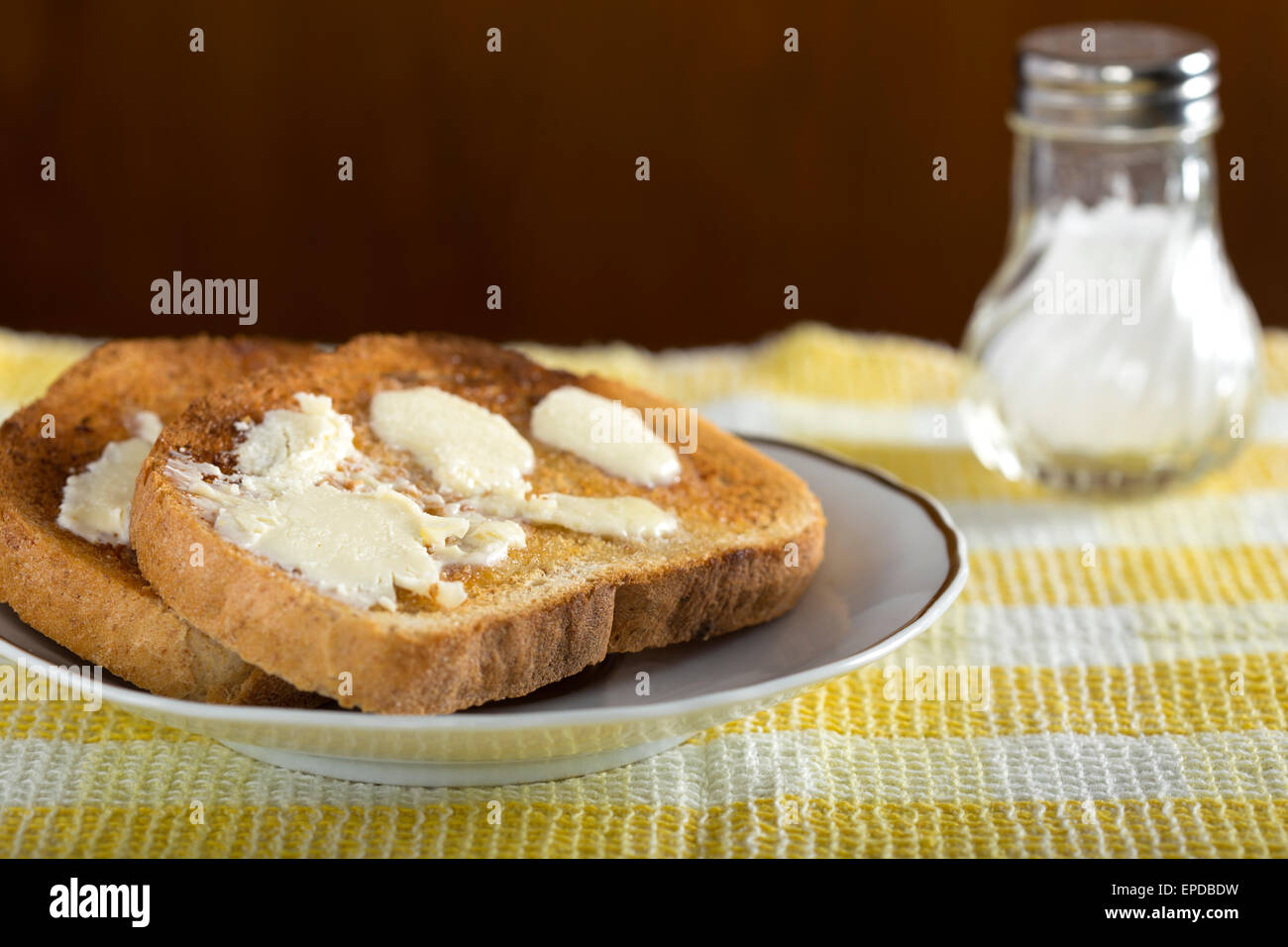 Zwei Scheiben weißen Toast mit Butter auf einen Teller mit Salz Stockfoto