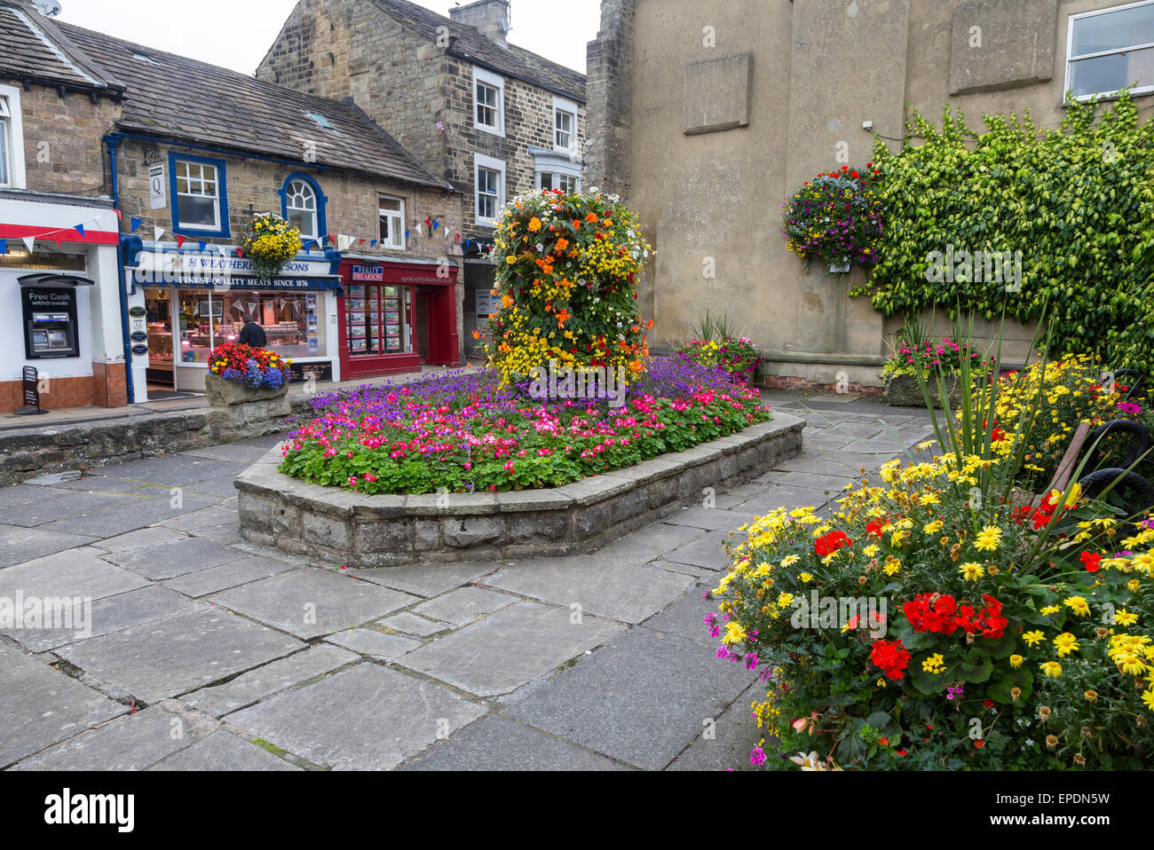 UK, England, Pateley Bridge, Yorkshire.  Dorfplatz, Blumen und Geschäfte. Stockfoto