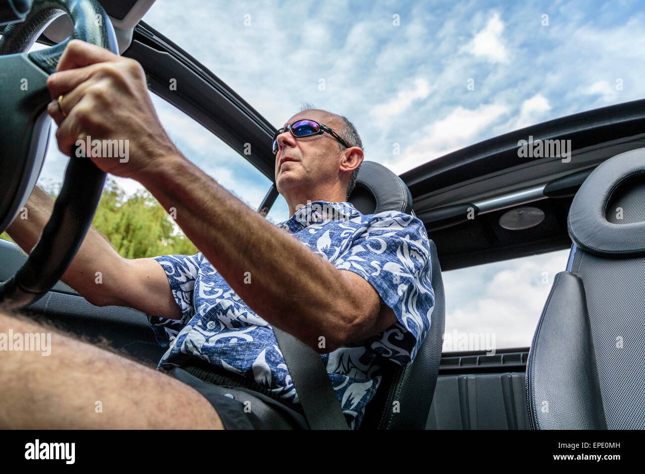 Ein Mann mittleren Alters mit einem Cabrio Auto mit dem Dach unten im Sommer in London, England, Großbritannien Stockfoto