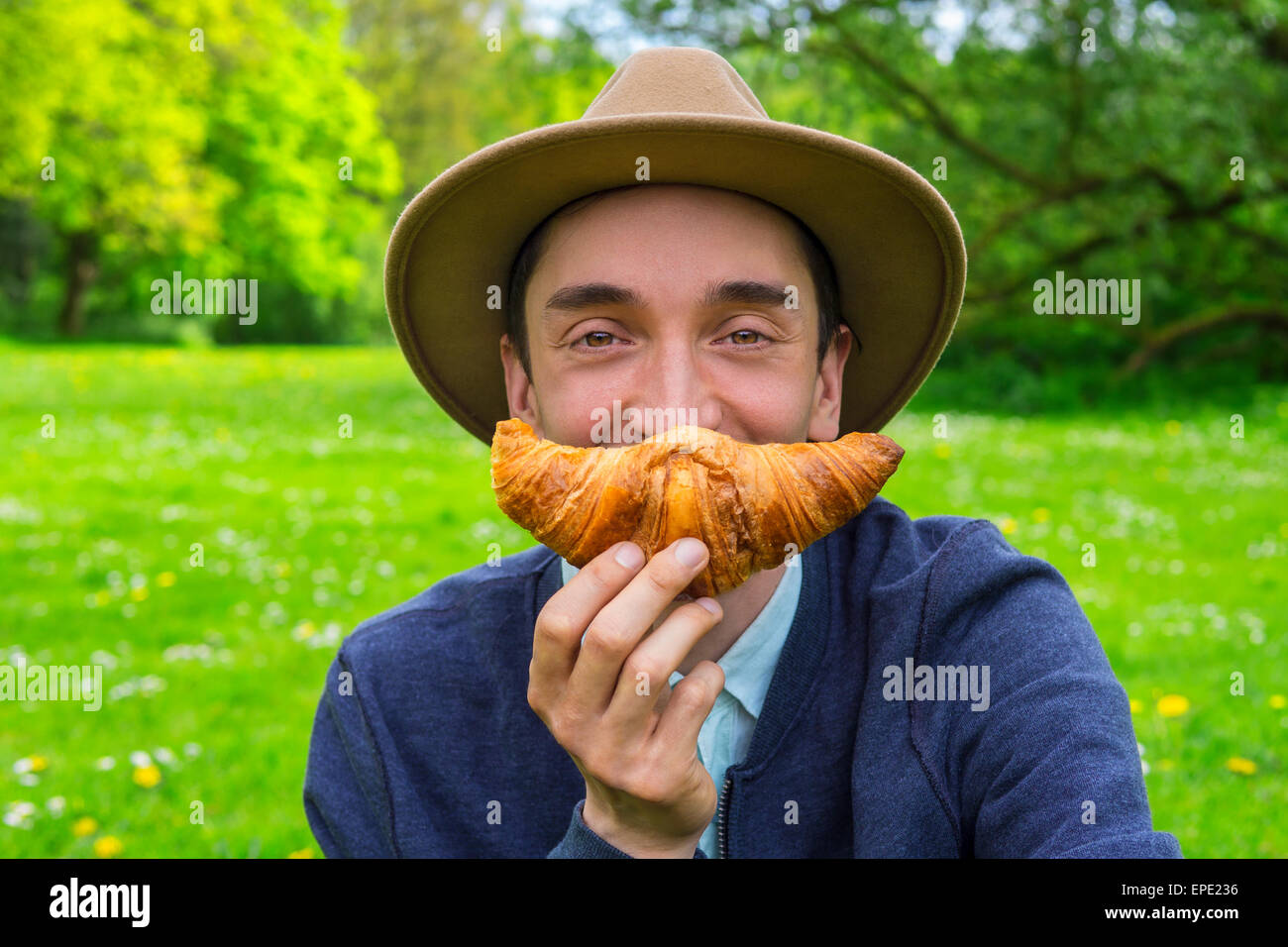 Stilvolle Mann isst eine Croissant im freien Stockfoto