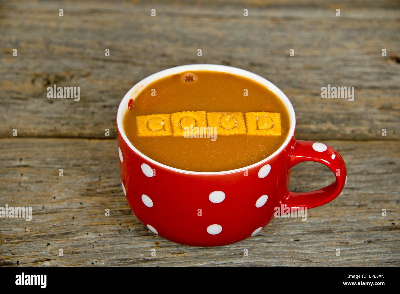 Tomaten Suppe und Käse-Cracker in einem roten Suppe-Becher mit weißen Tupfen auf rustikalen Holz. Stockfoto