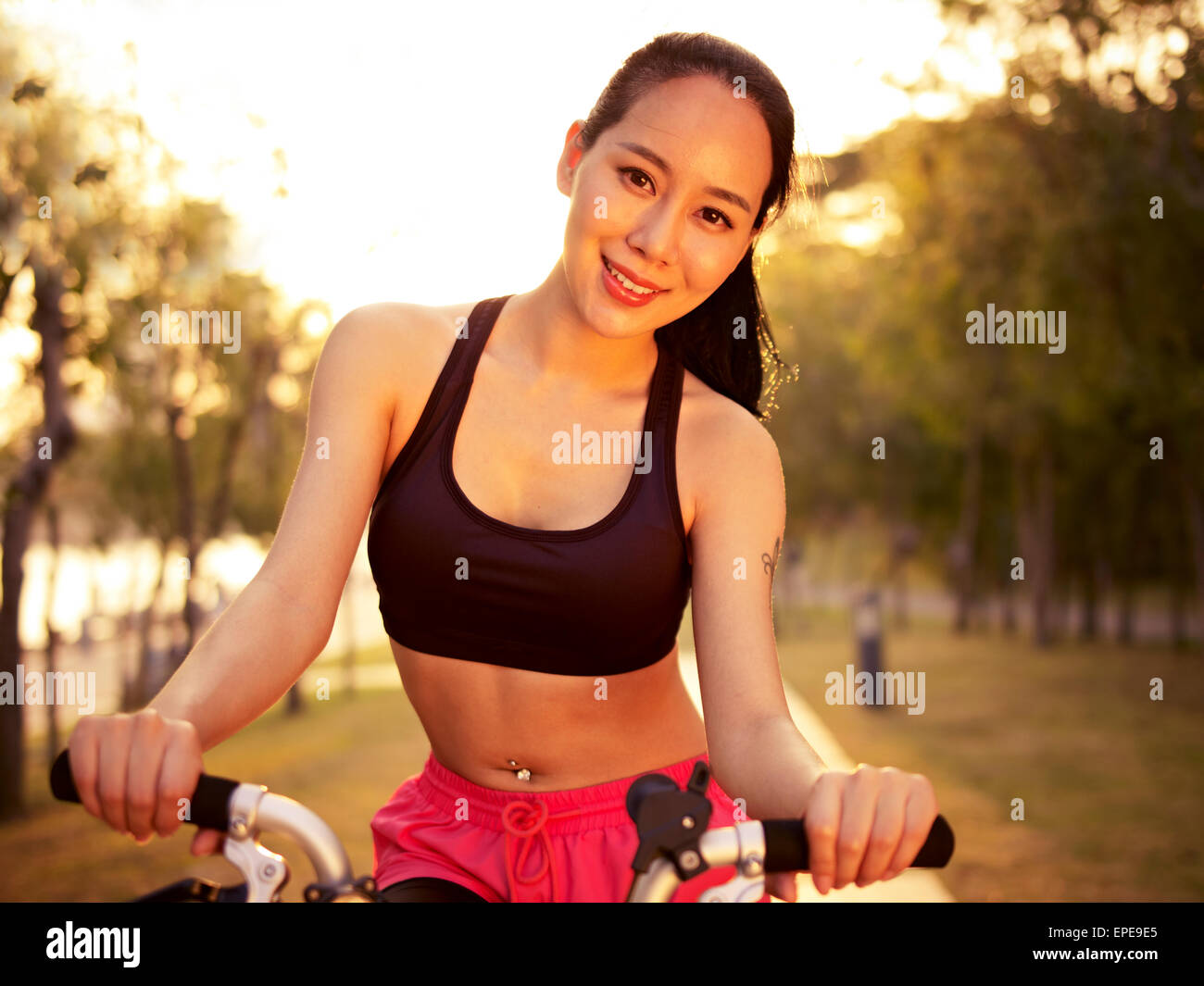 junge Frau Reiten Fahrrad im Park bei Sonnenuntergang Stockfoto
