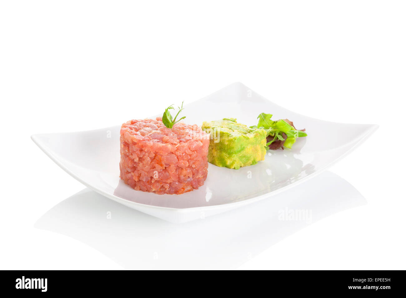 Leckere Thunfisch-Tatar mit Avocado-Dip und frischem grünen Salat auf Teller auf weißem Hintergrund. Gehobene Küche. Stockfoto