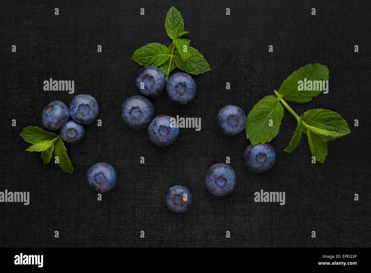 Heidelbeeren auf schwarzem Hintergrund mit grünen Minze isoliert. Gesunde frische saisonale Obst essen. Stockfoto