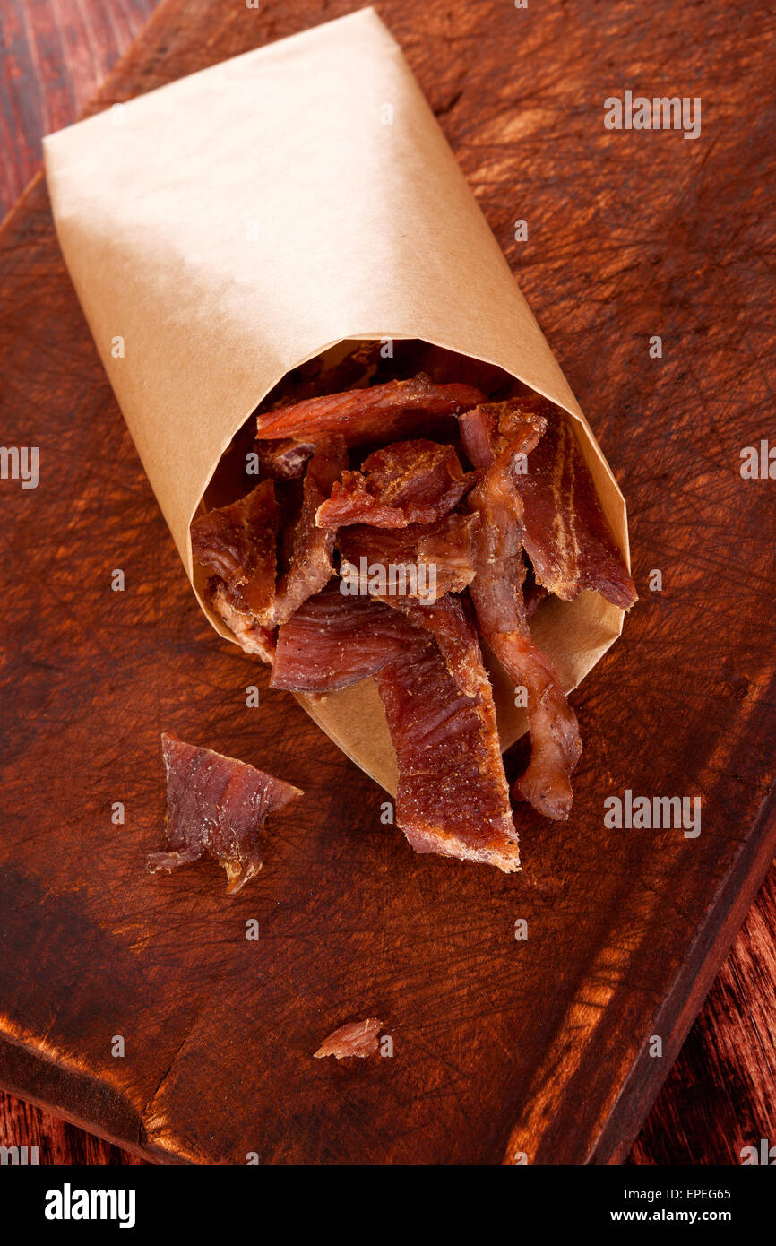 Dörrfleisch. Trockenfleisch Dörrfleisch auf Schneidbrett aus Holz auf Holz Hintergrund. Trockenfleisch, rustikalen Landhausstil. Leckeres Fleisch Stockfoto