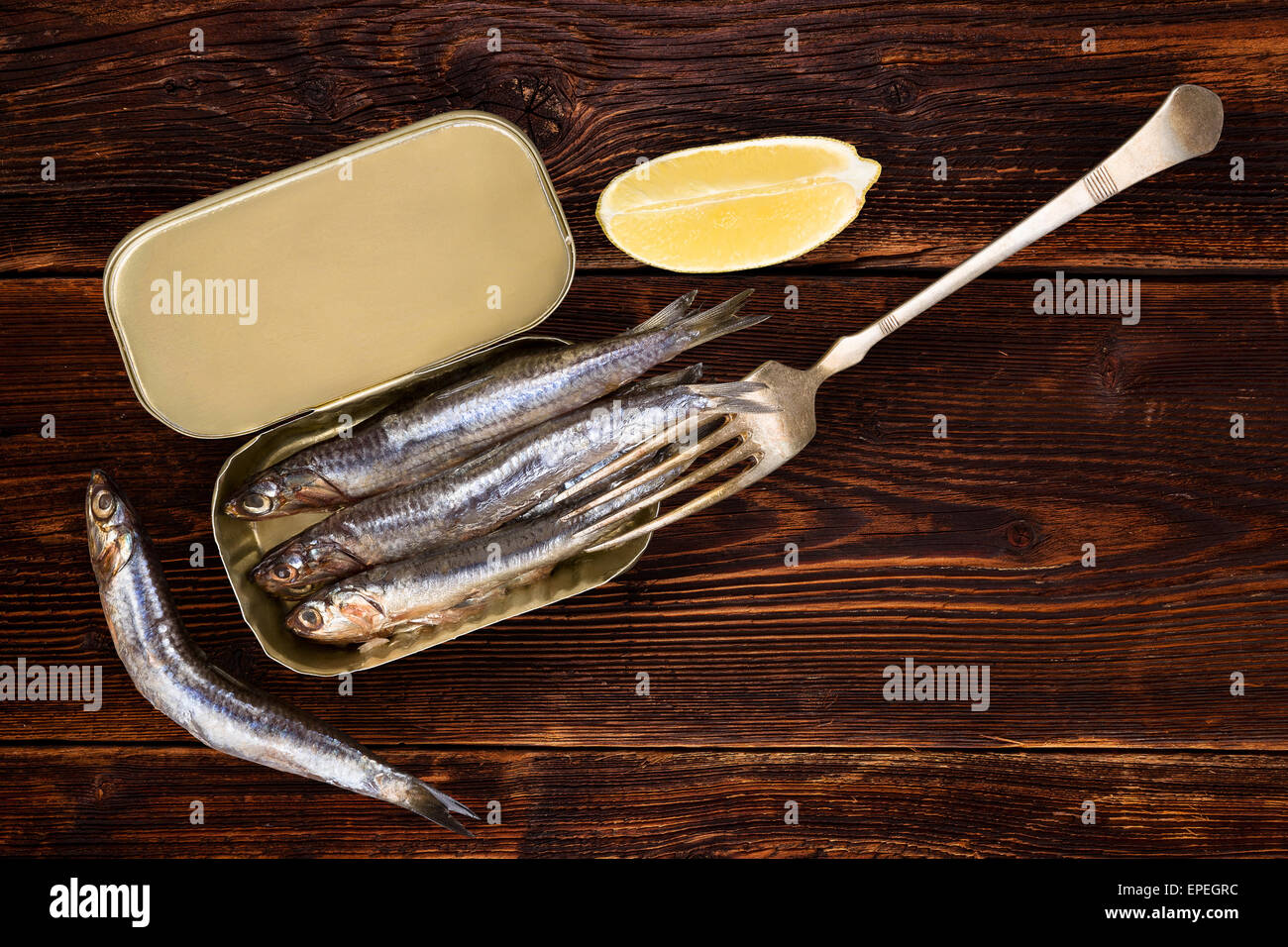 Sardinen auf alten hölzernen strukturierten Hintergrund mit Zitrone Stück. Kulinarischen gesunde Fische essen. Stockfoto